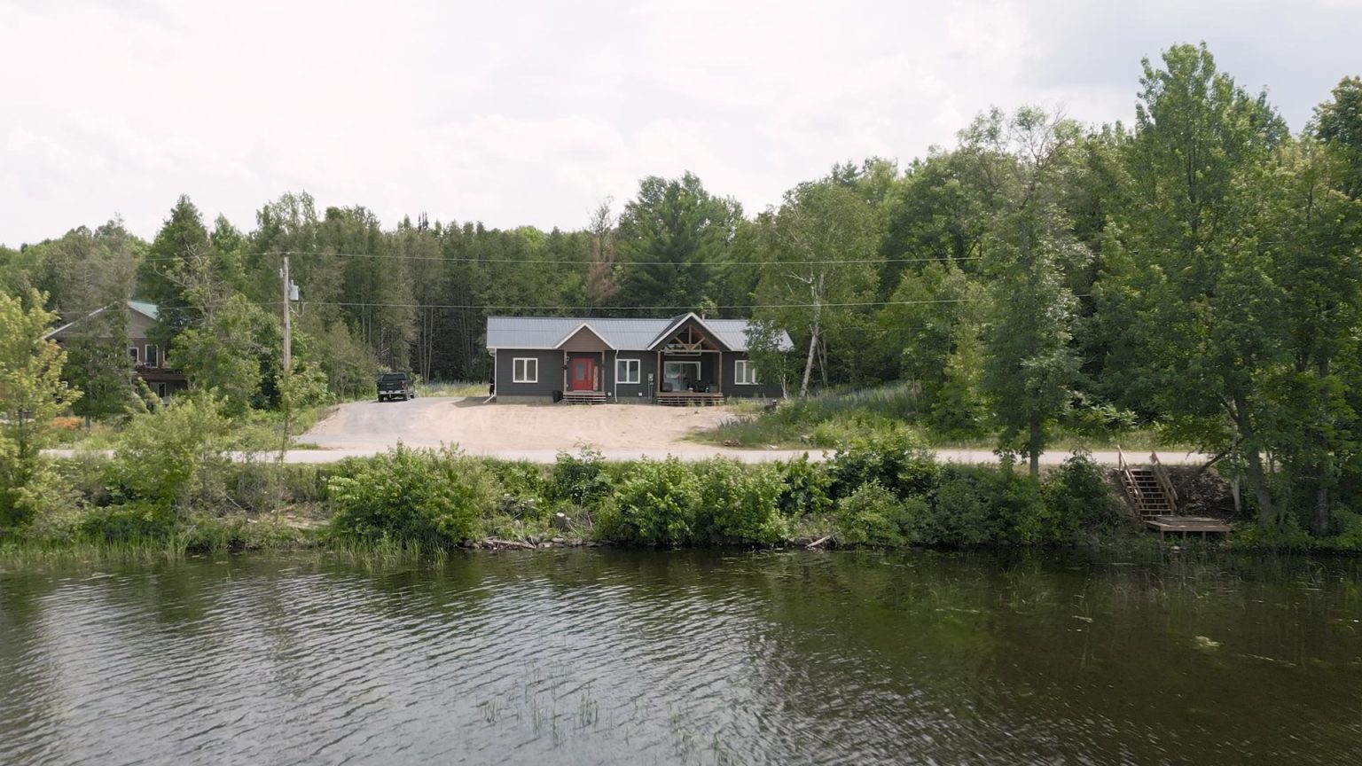 A house located by the riverbank, surrounded by trees.
